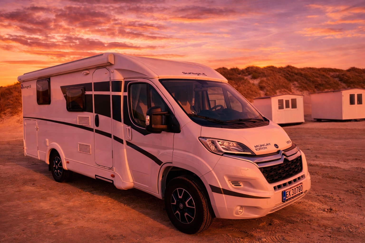 Autocamper parkeret ved klitter i solnedgang ved stranden
