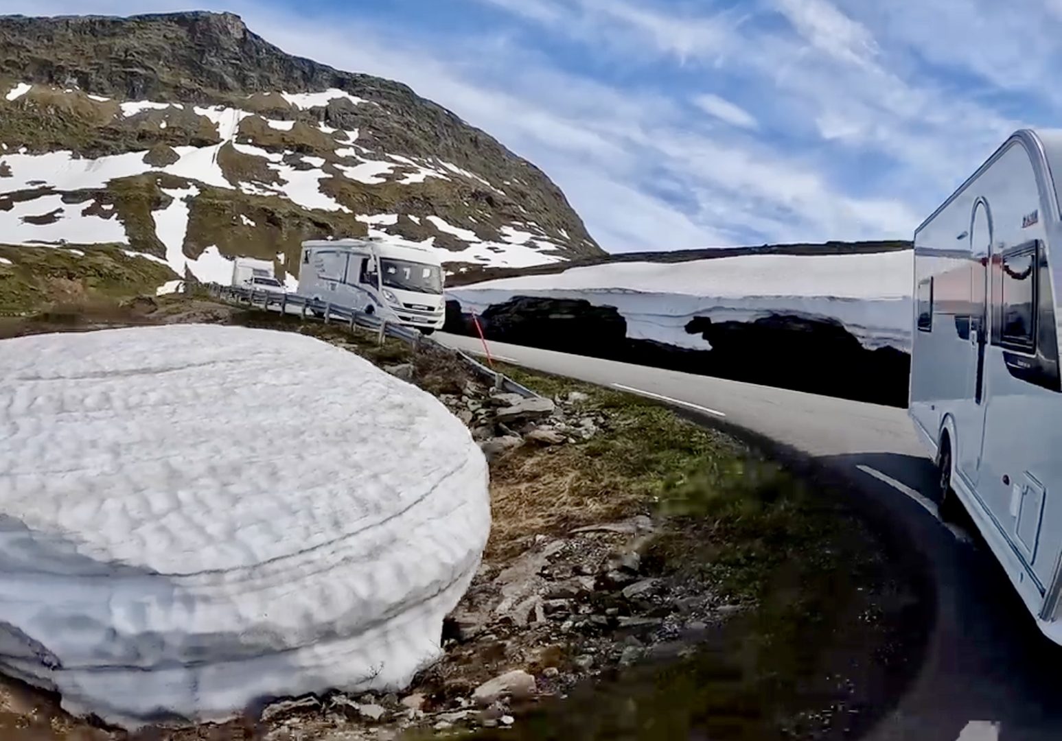 Autocamper og campingvogn på fjeldvej med sne i Norge, Geiranger